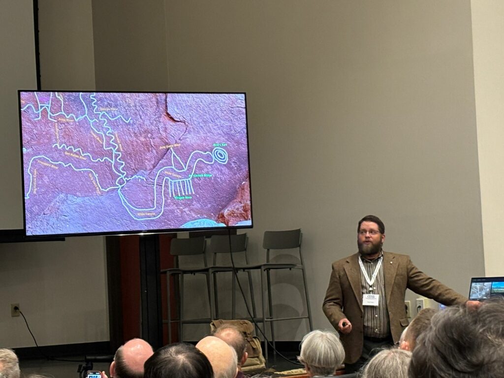 Nate Loper Giving a Geology Conference Presentation Nate Loper giving a conference presentation with a detailed geology map on screen
