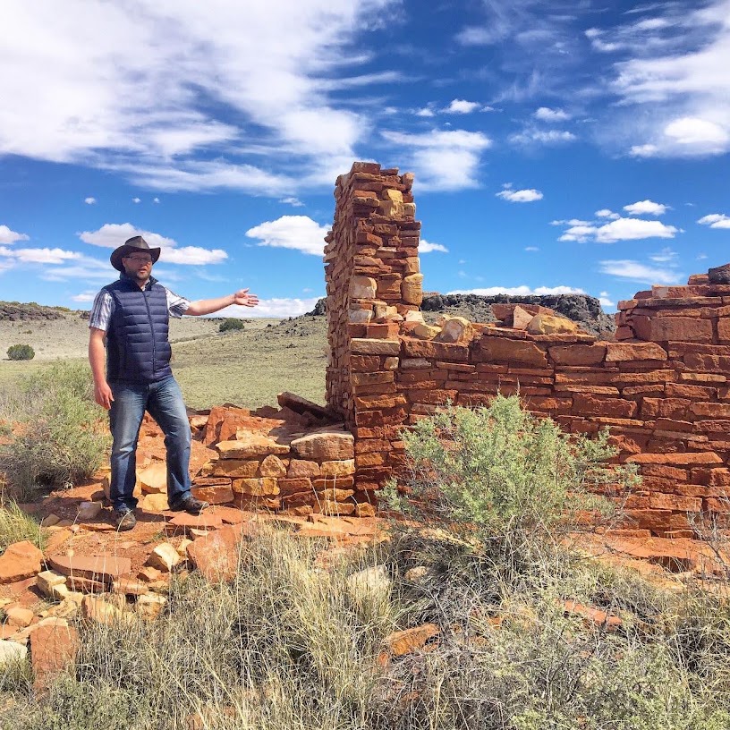 Nate Loper teaching archaeology beside the stone walls of Lomaki Ruin at Wupatki National Monument