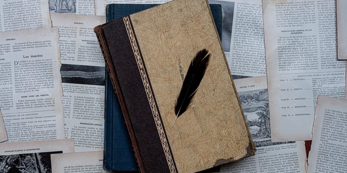 Vintage book and quill atop aged manuscript pages